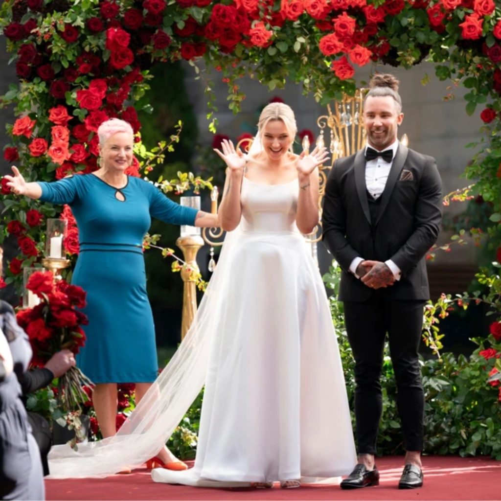 Tori and Jack stand in front of a wall of red roses during their wedding in married at first sight australia 2024