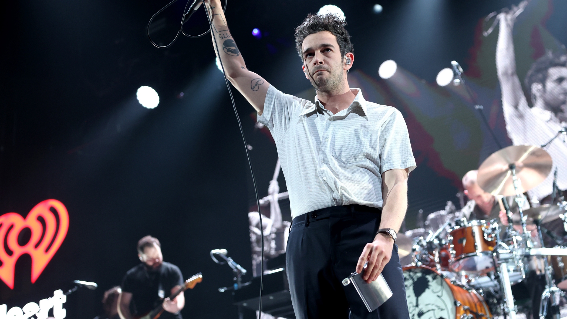 matty healy on stage holding a silver flask and microphone (story: why do good girls like bad boys?)